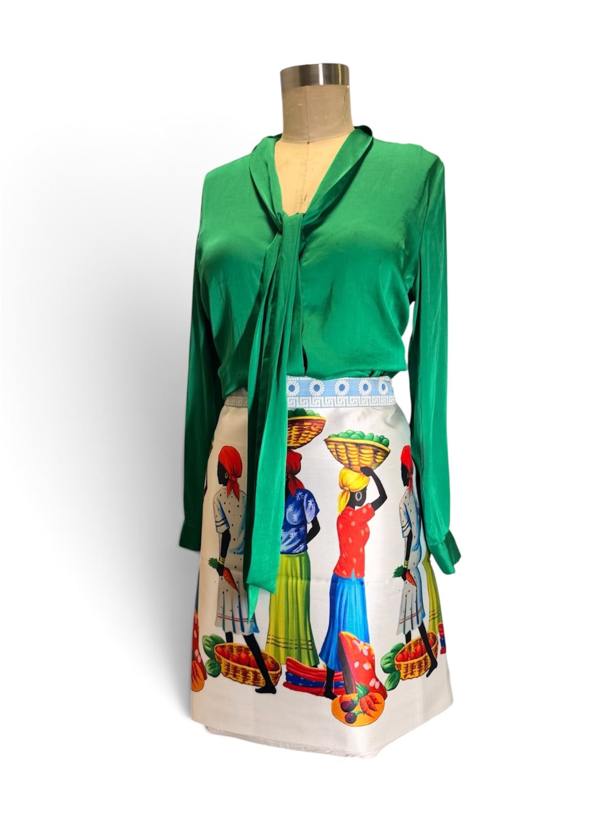 El conjunto Frutera: blusa esmeralda con lazo sobre la falda de fruteras, fotografiado en el taller.