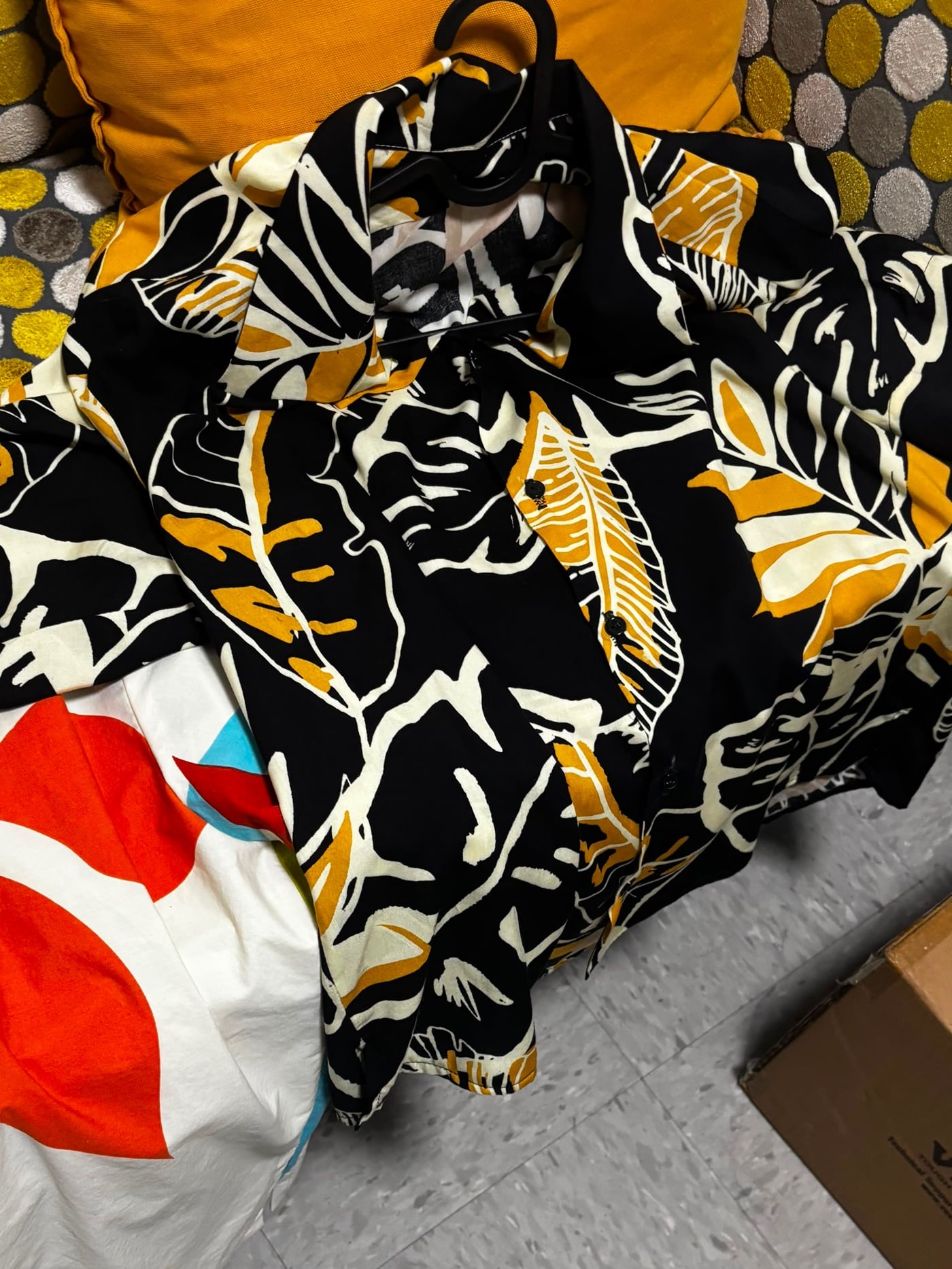 La camisa campera Guanaba en estampado de hoja tropical negro, crema y amarillo, en su gancho en el taller.
